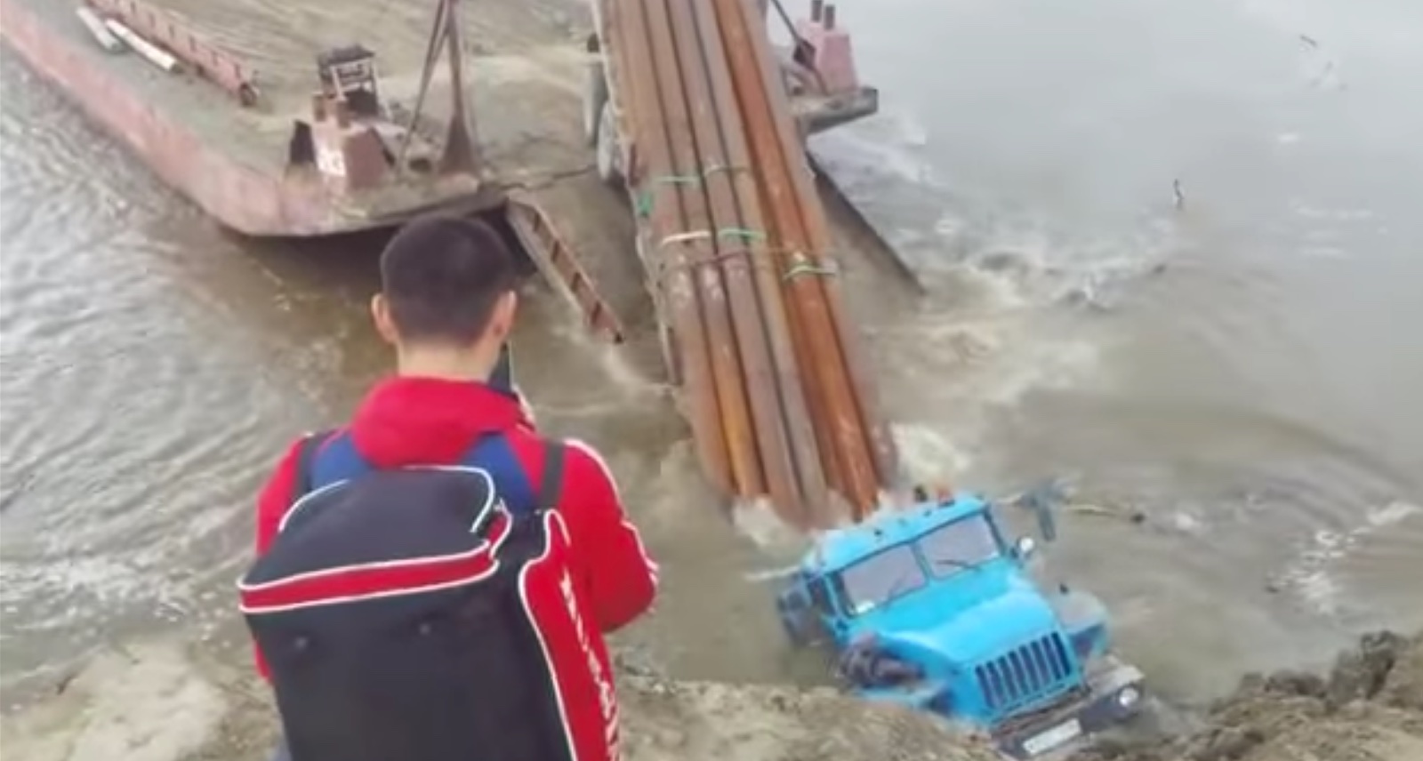 Sinking truck tries to load pipes onto unmoored barge
