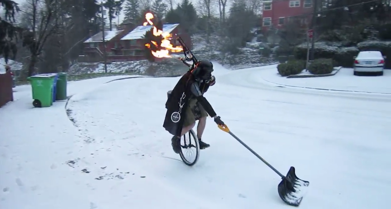 Man plays flaming bagpipes while dressed as Darth Vader riding a unicycle
