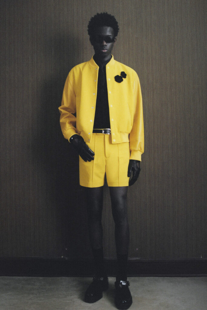 Man in yellow suit standing in front of black background