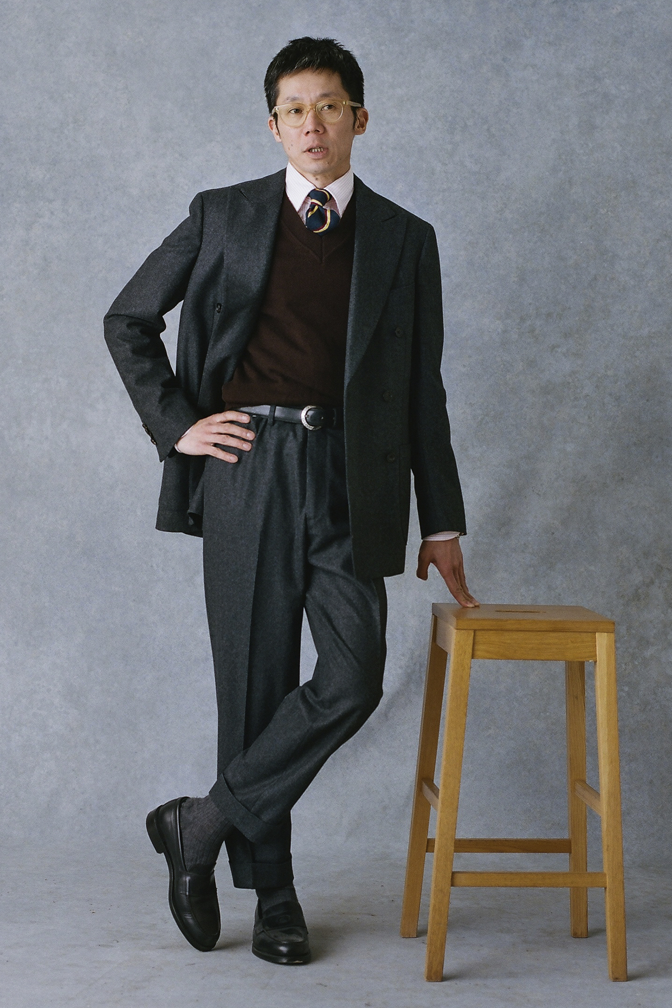 Man in suit leans against stool