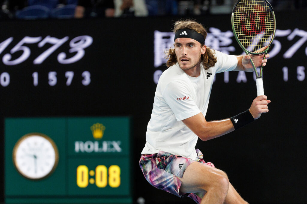 Stefano Tsitsipas plays tennis in front of Rolex sign