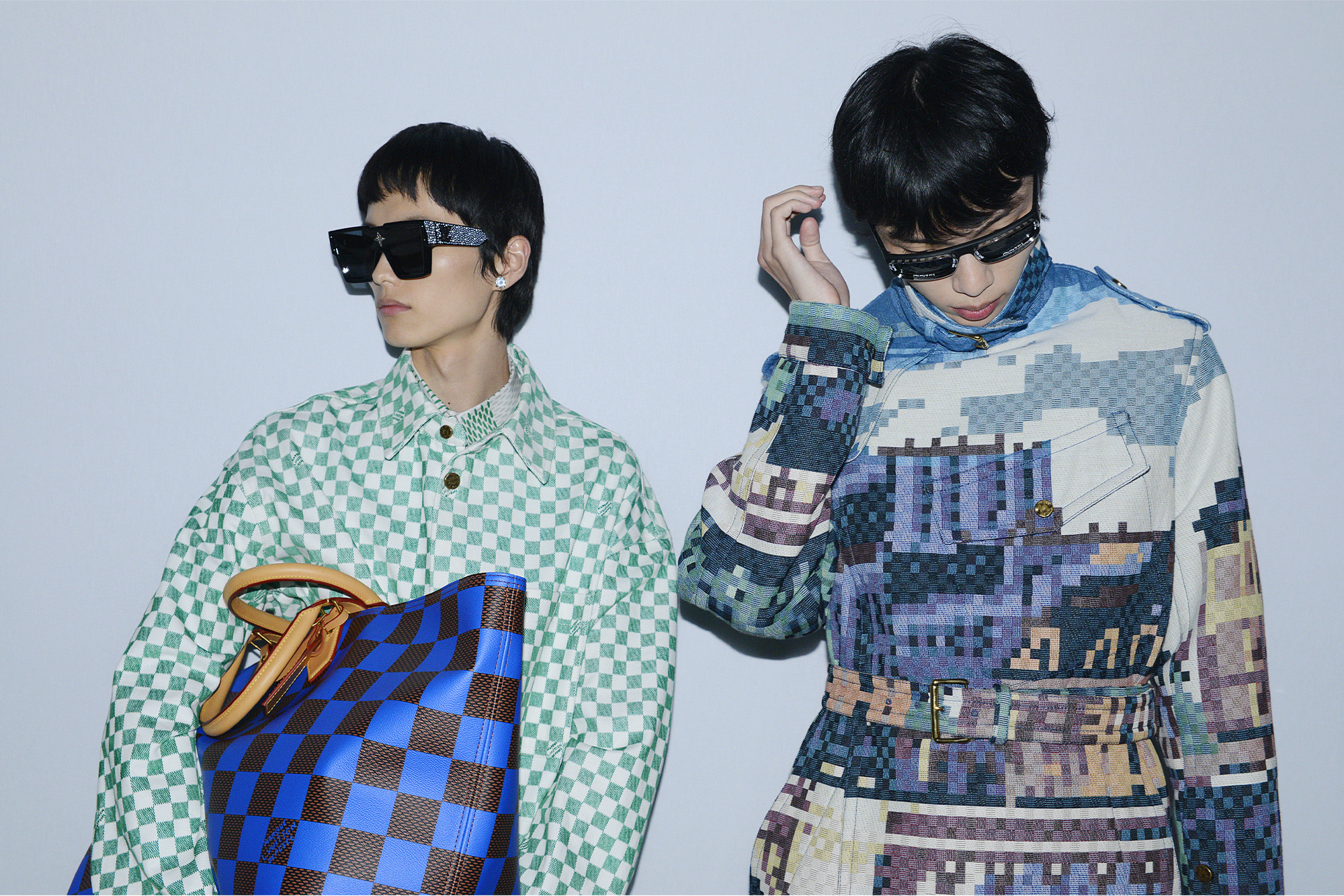 Pharrell Williams Louis Vuitton Men's Spring-Summer 2024 two models in graphic and checkered outfits with bags