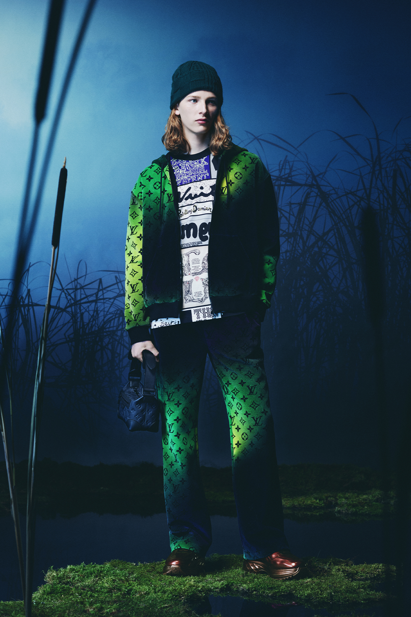 Louis Vuitton Men's Collection Pre Spring/Summer 2024 model in forest wearing green checkered patterned jacket and pants with graphic tee