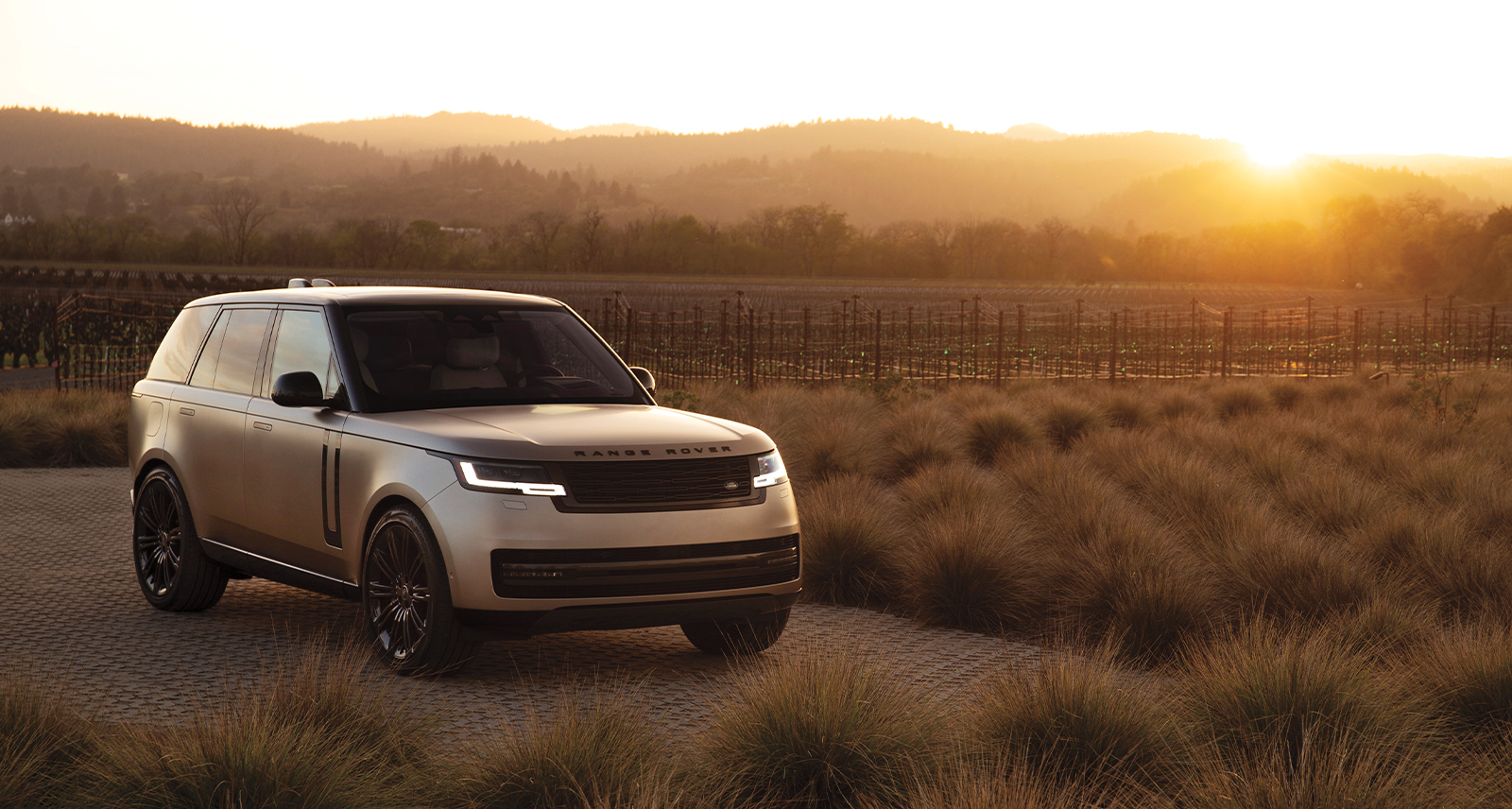Range Rover on a field in California, with mountain sunset in back