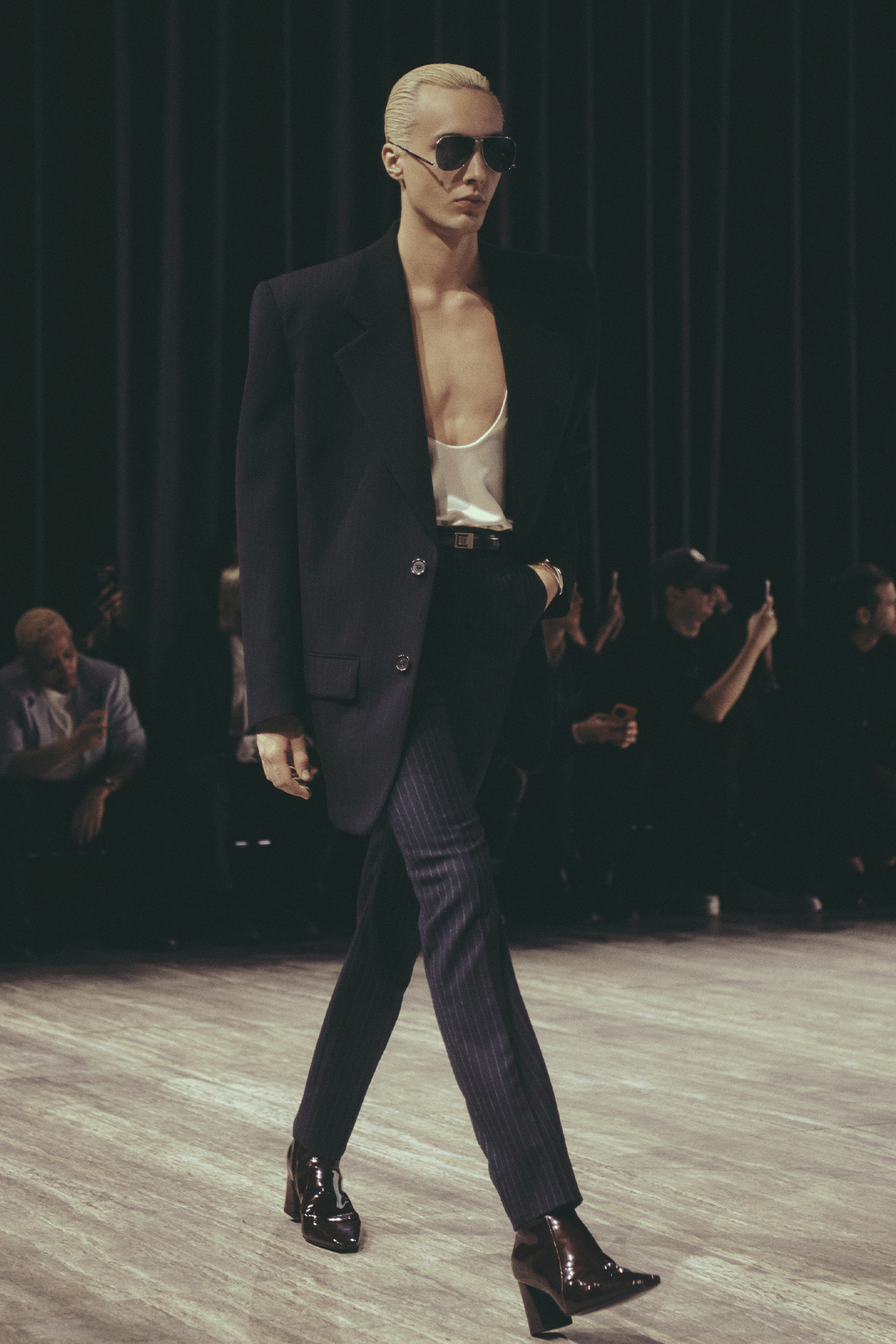 Saint Laurent Spring/Summer 2024 menswear model walking in suit with low cut tank top and jacket