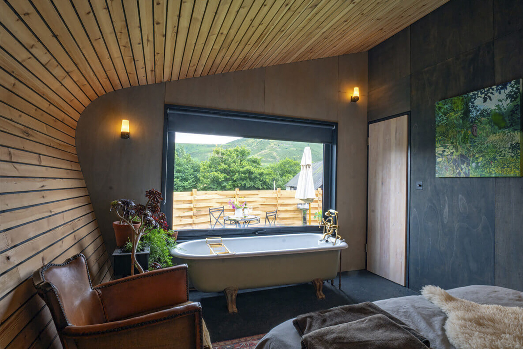Hergest Lee Cabin & Lean-To Cabin in Wales, UK for rent. interior shows curved wooden side on the left curling up towards the ceiling with window