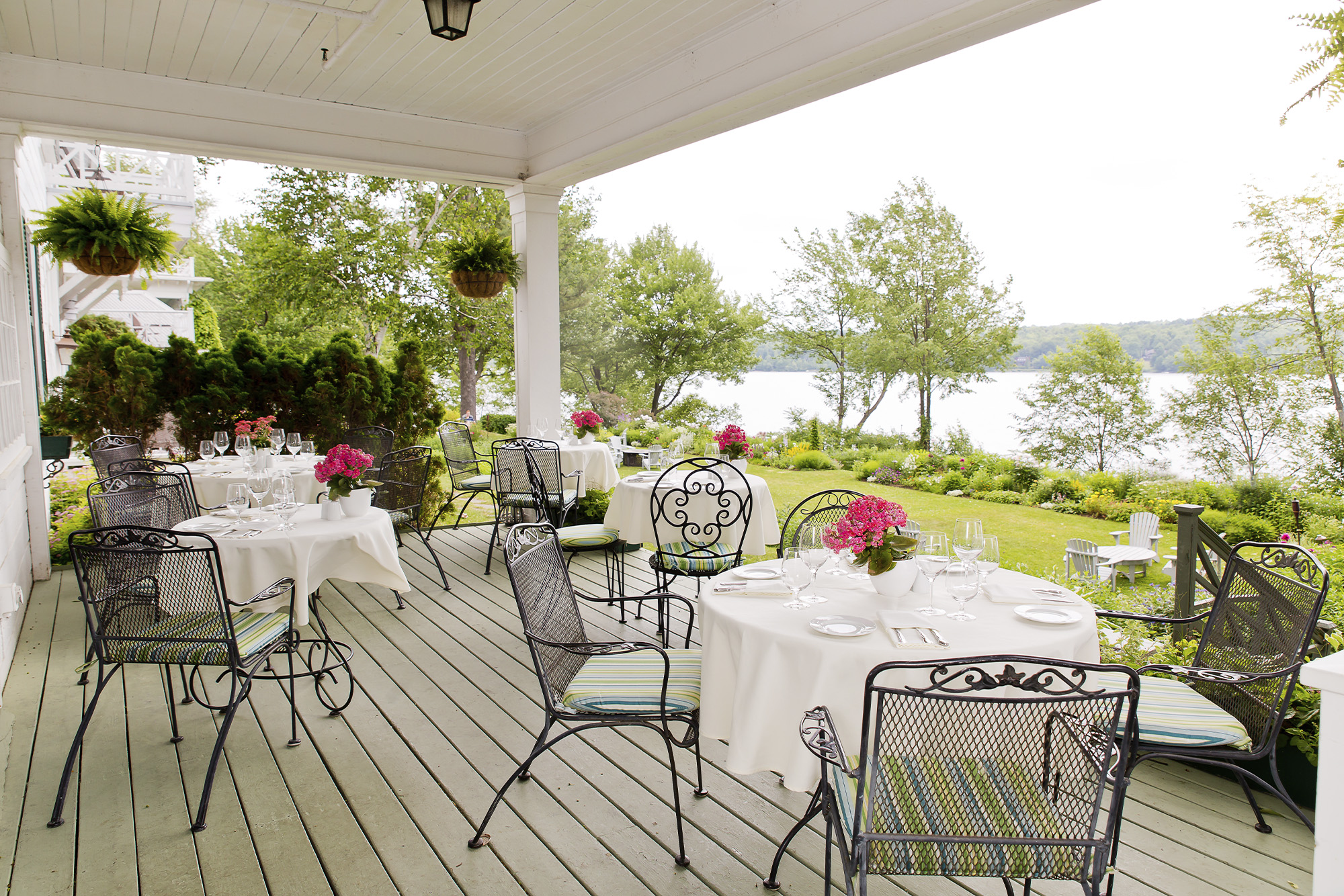 Le hatless patio wired black chairs and white tablecloths look out to view of lake