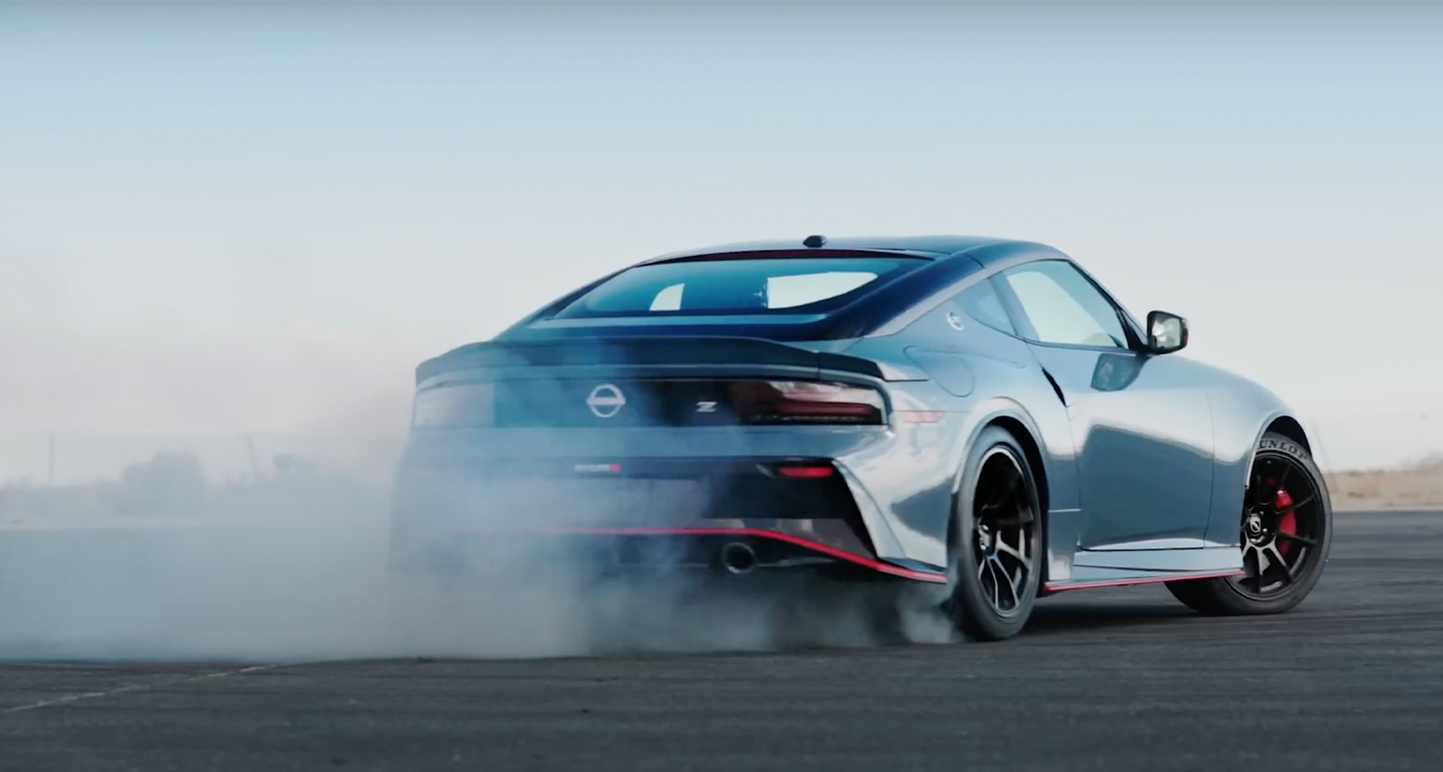 Nissan NISMO Z from back driving on race track with dust cloud behind it