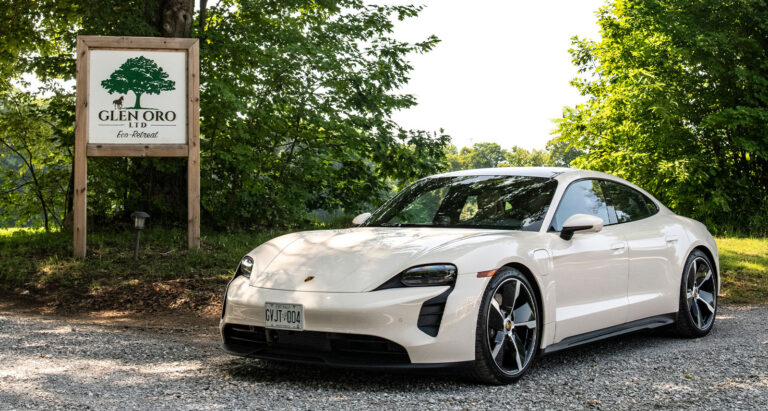 Porsche Taycan GTS parked by sign with trees
