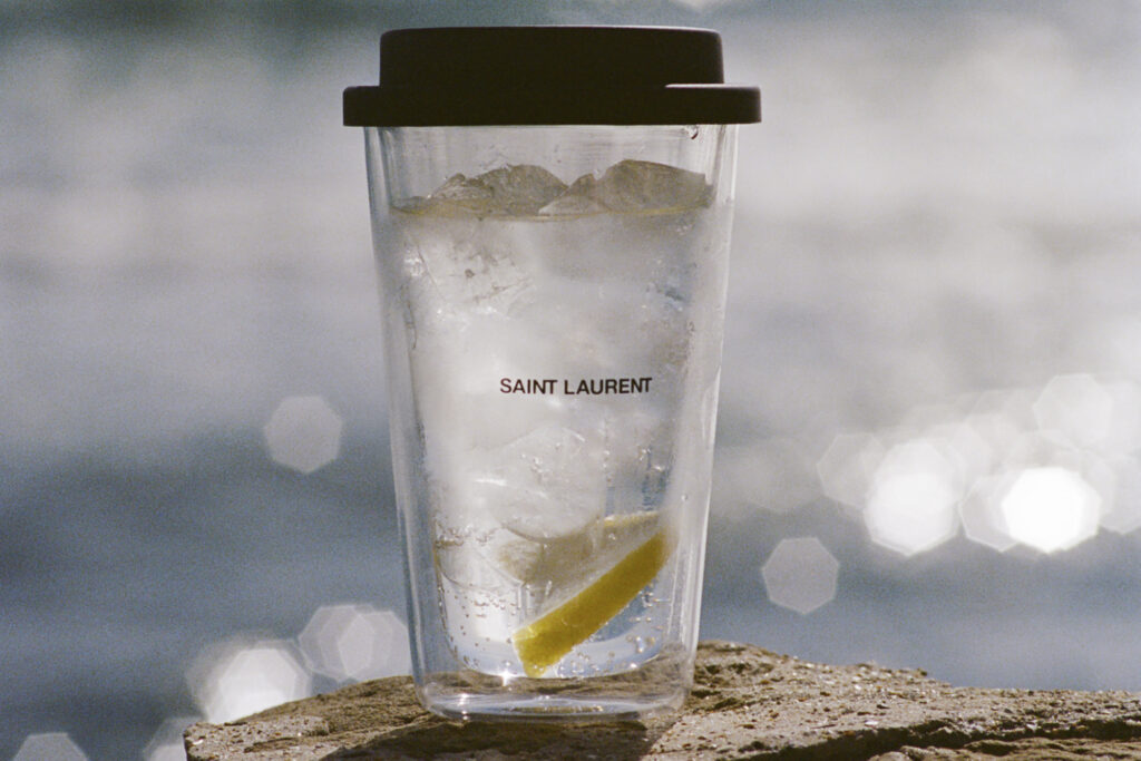 Saint Laurent Rive Droite collection travel cup with water on beach rock with ocean view