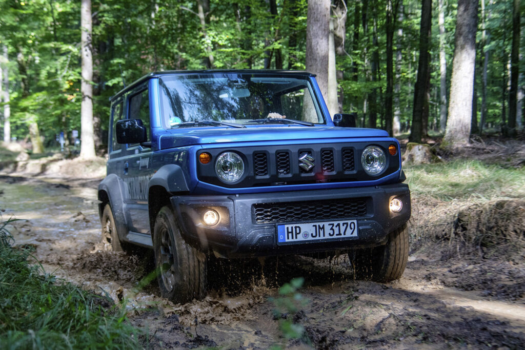 Blue Suzuki Jimny driving through woods