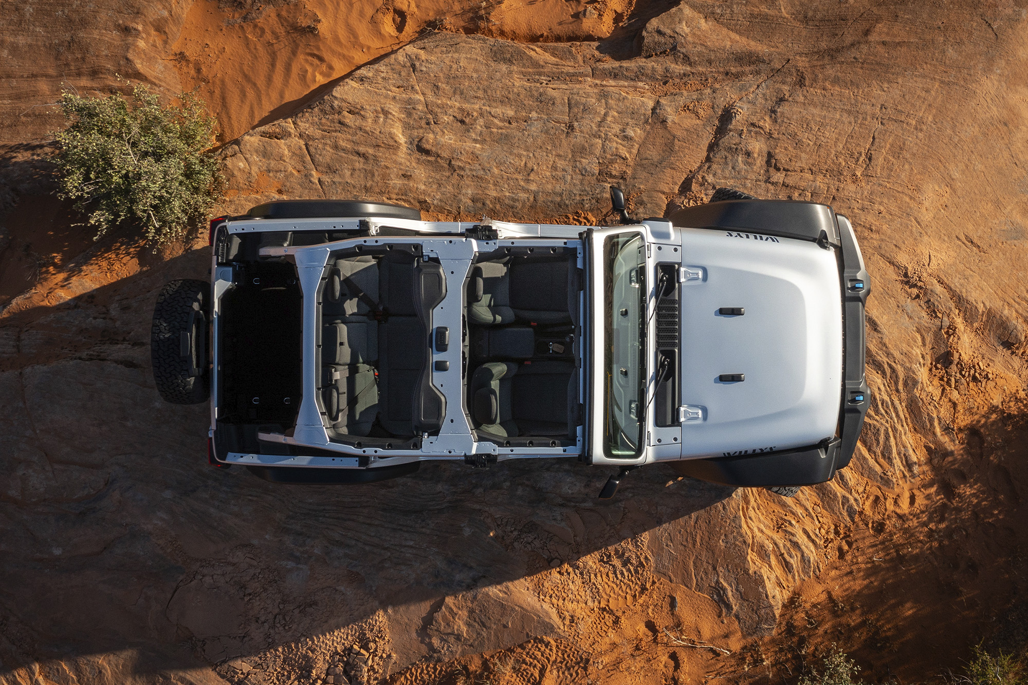Bird's eye view of the top of a silver Jeep Wrangler parked in desert