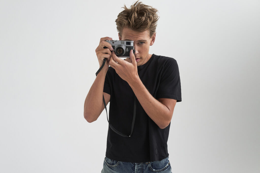 Austin Butler poses with camera held up to face on white background
