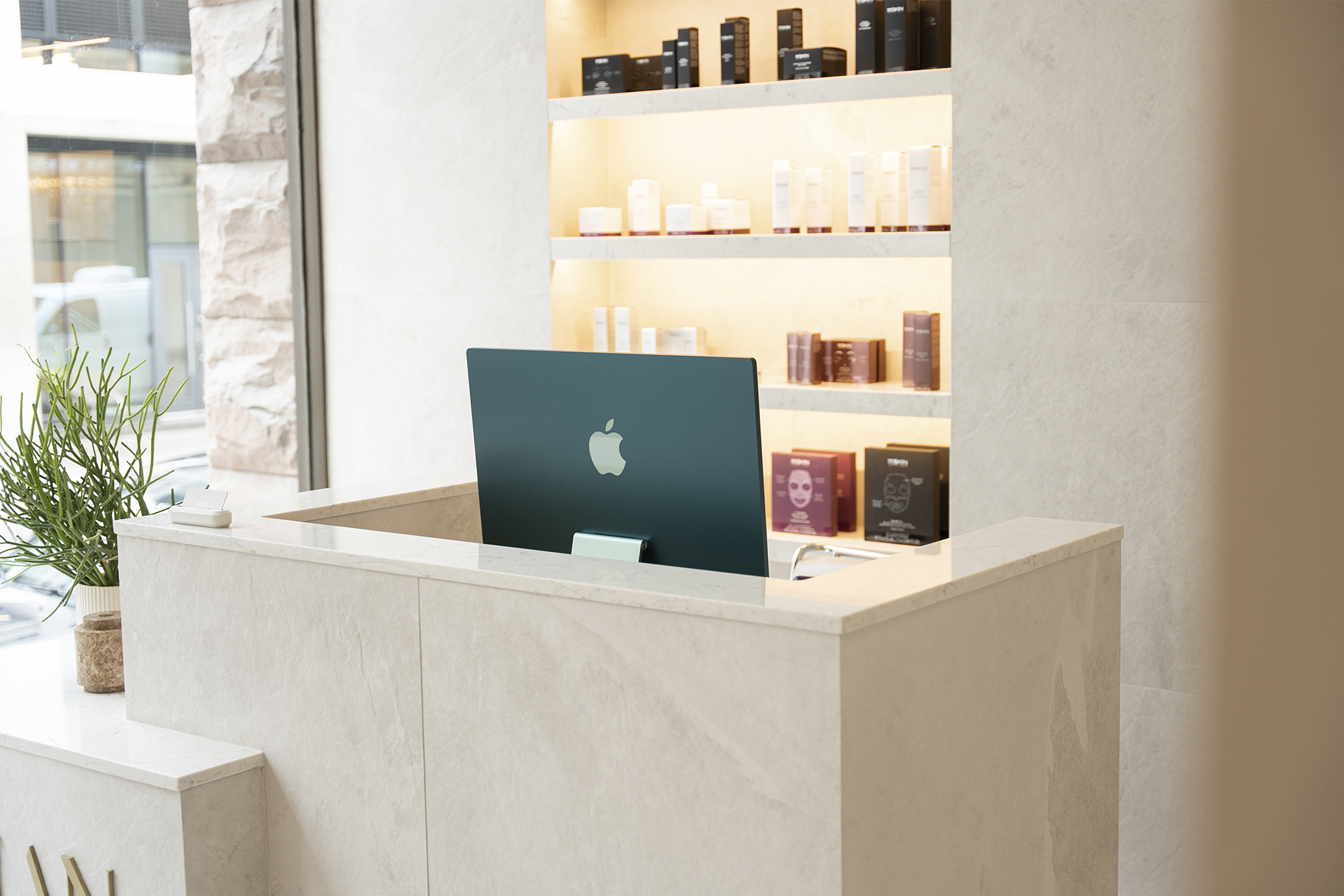 Aman Spa front desk, with shelf of products behind desk, Mac computer on front desk