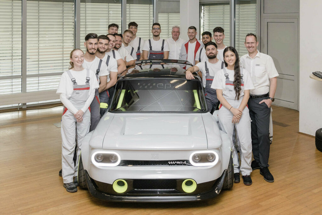 Audi / NSU Prinz e-tron students surround the vehicle, shot from front view
