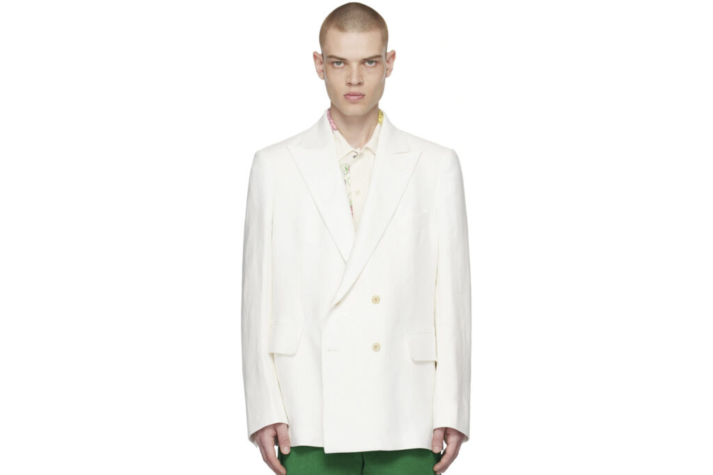 Model wearing Bode double-breasted white blazer over white undershirt and green pants