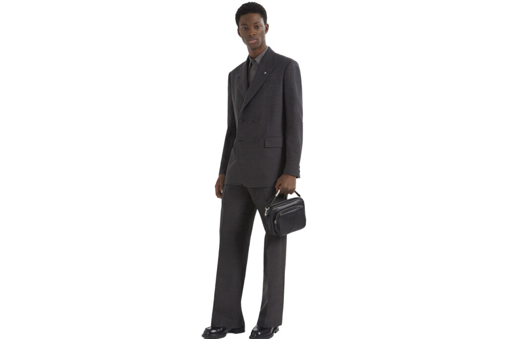 Model wearing Fendi double-breasted suit jacket with pants and holding a small bag