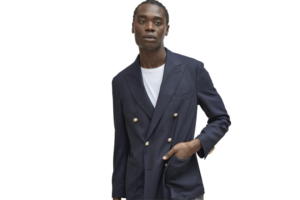 Model stands wearing navy Harold double-breasted jacket and white undershirt