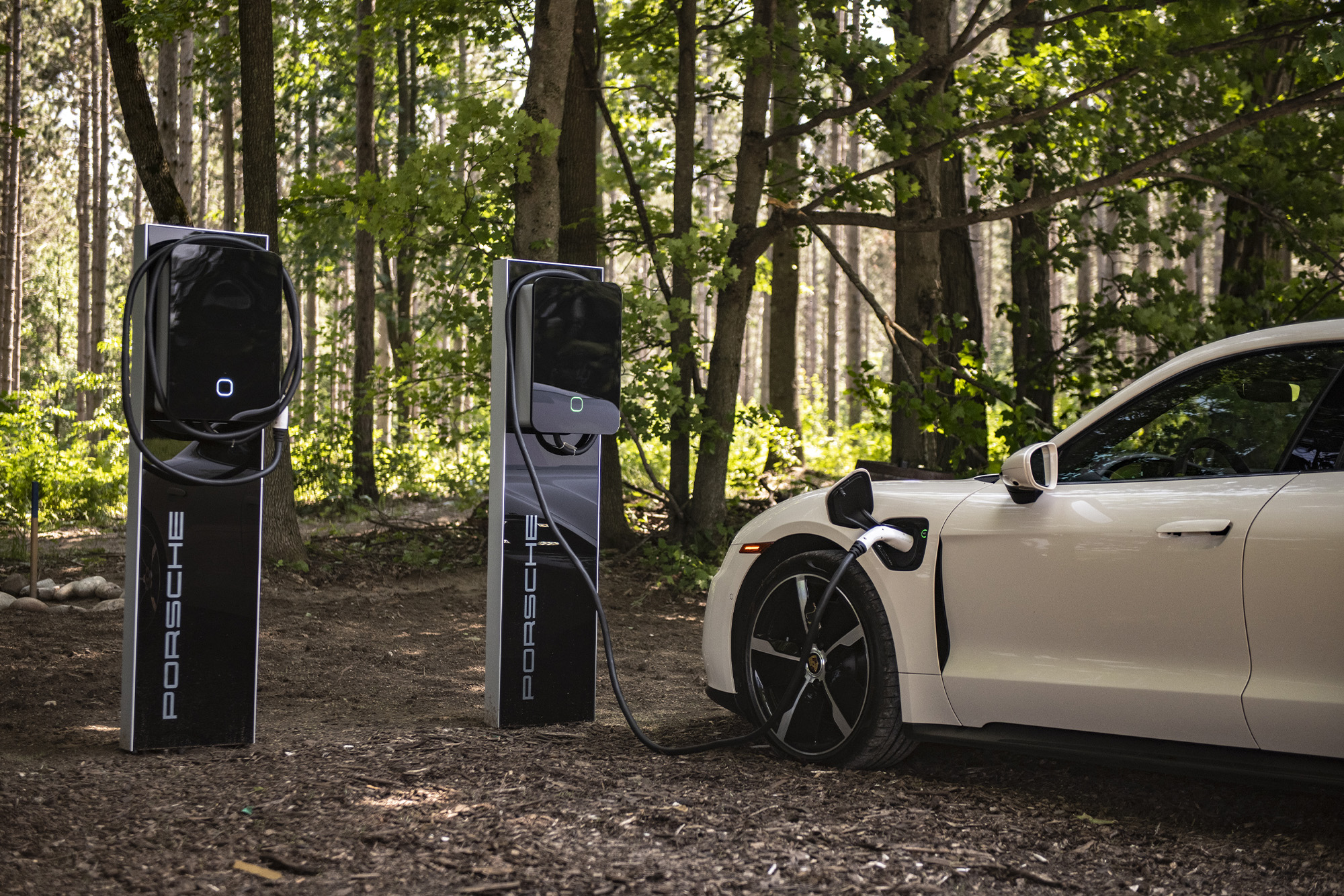 Glen Pro Farm Porsche Charging Station: white Porsche charges on one charging station in the woods on the righthand side, the other charging station is open