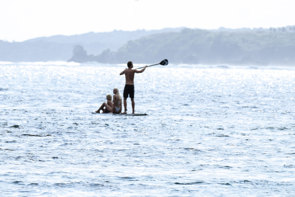 Three people on a paddle board in the ocean by Sanubari Sunda, Indonesia
