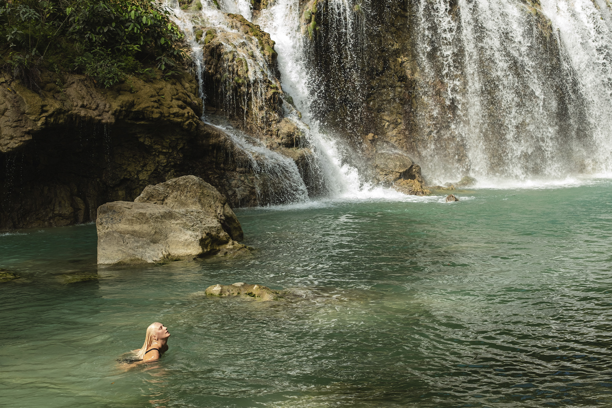 someone swimming in a waterfall in Indonesia