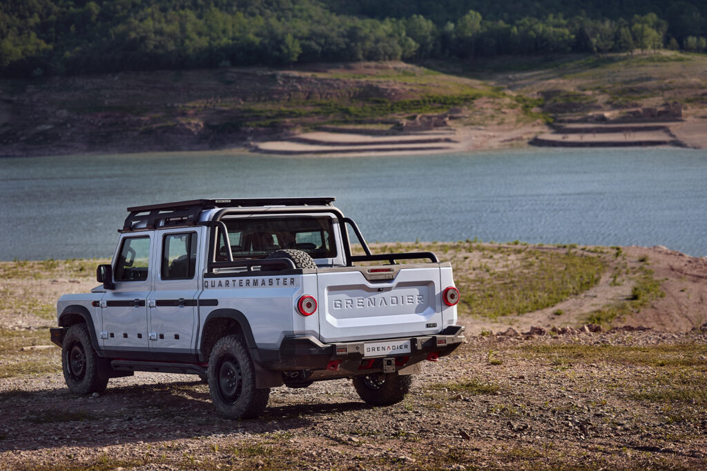 Ineos Grenadier Quartermaster parked on a dry dirt road by a river, shot from the back