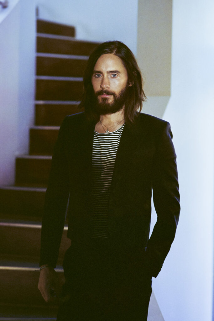 Portrait of Jared Leto in black suit with striped undershirt by wooden stairs for SHARP September