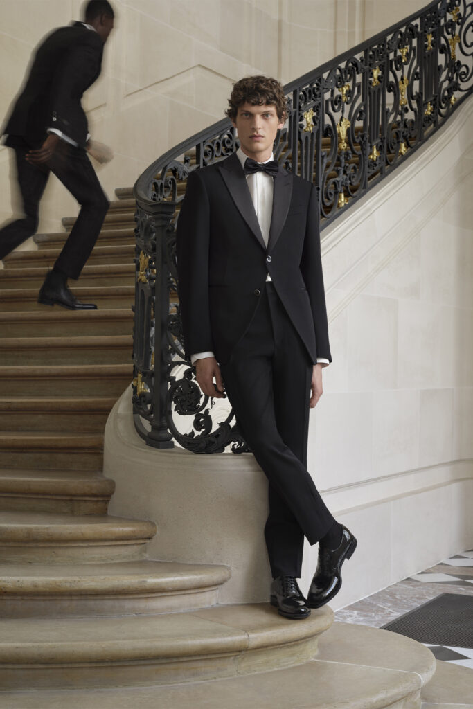 Model wearing a Louis Vuitton tux stands and poses at the bottom of the stairs 