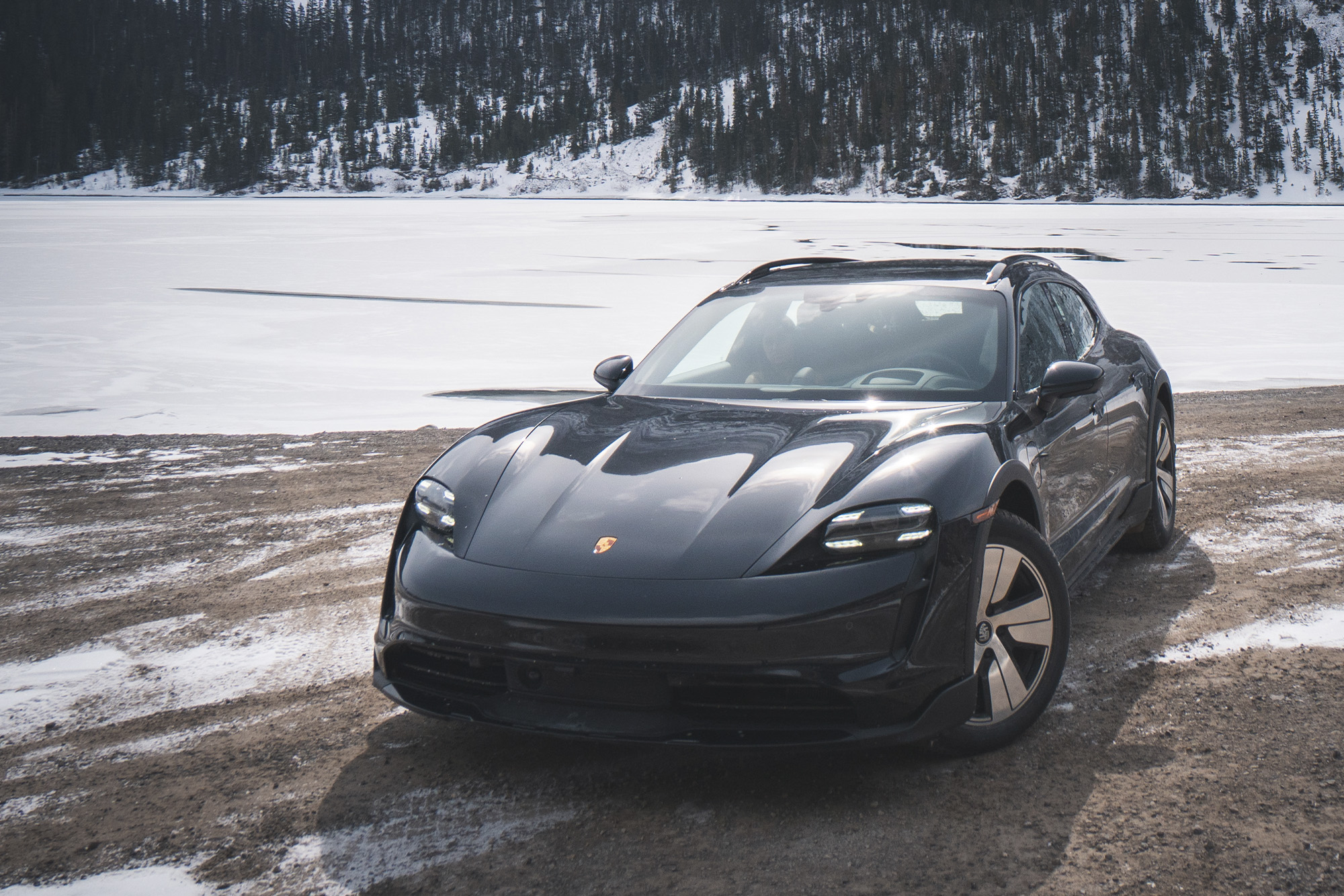 Black Porsche parked at Panorama Mountain Resort & Greywolf Golf Club on dirt road with snow in the background, shot from above the front