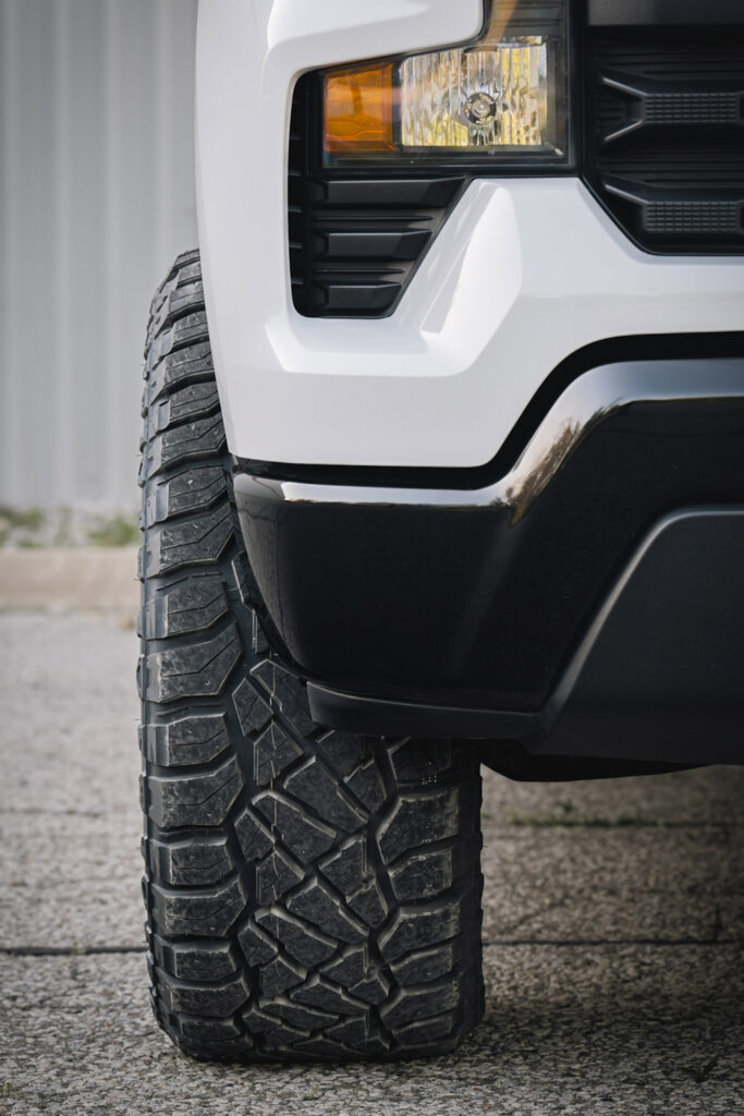Rugged terrain tire close up under white truck