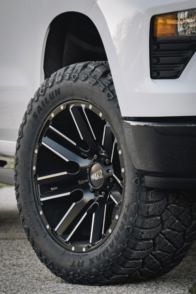 Rugged terrain tire close up under white truck