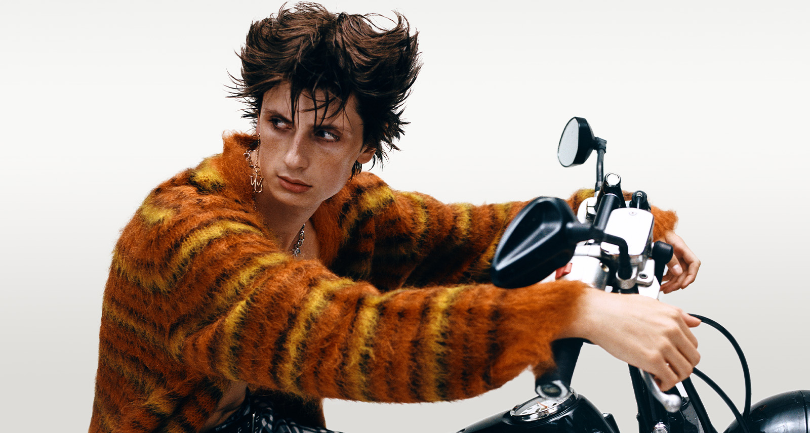 Model in fuzzy orange sweater on motorcycle
