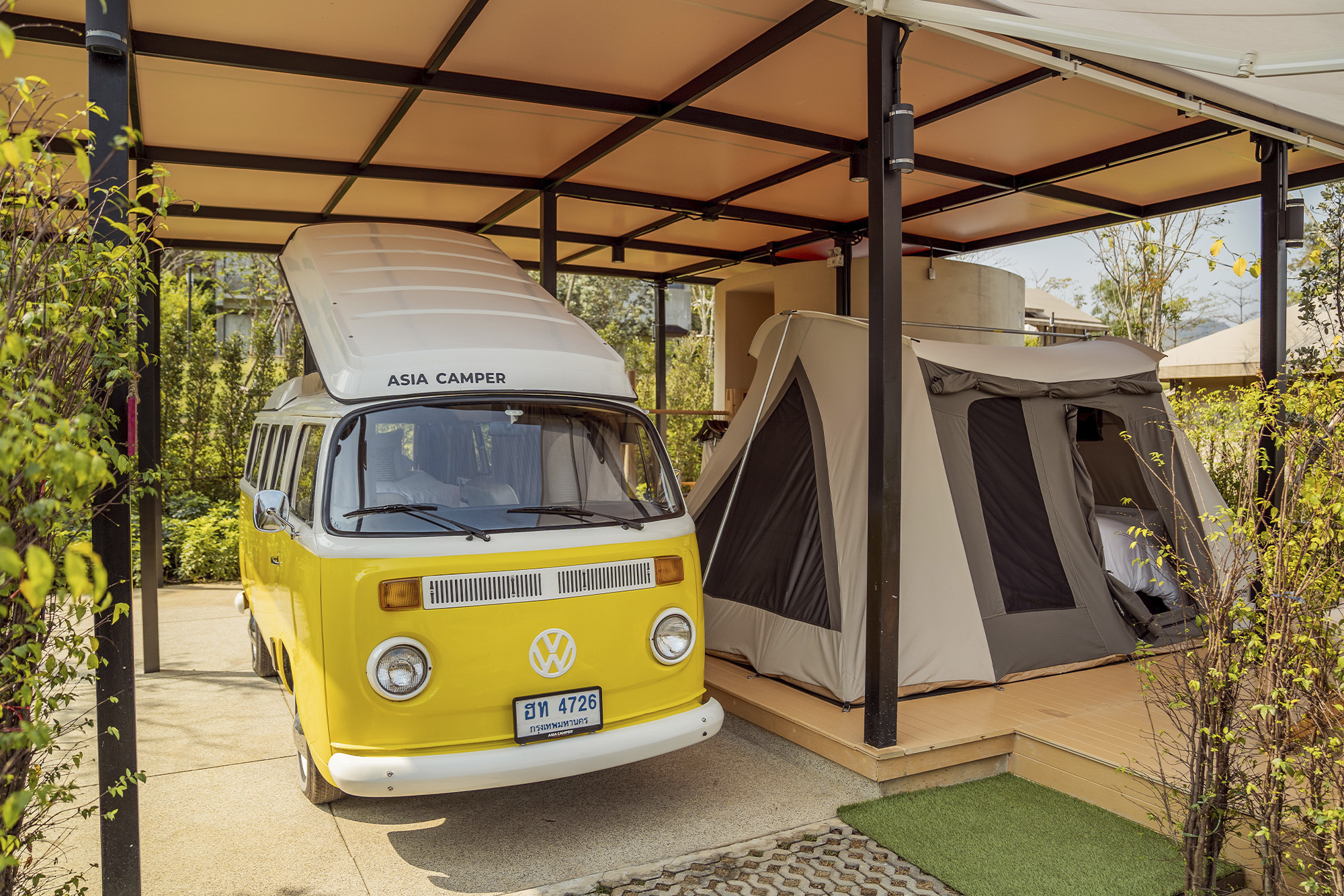 YEllow VW van parked under awning by a tent in Marasca Khao Yai, Thailand