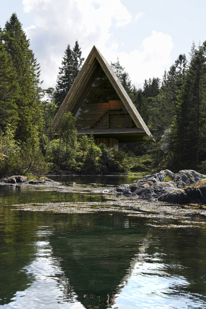 Bjarke Ingles Group (BIG) project on Vollebak Island: triangular a-frame cabin pokes out from pine trees to overlook and sandy beach and water