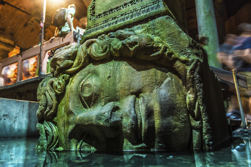 Medusa head on its side at the bottom of a column inside the Basilica Cistern, a tourist spot in Istanbul