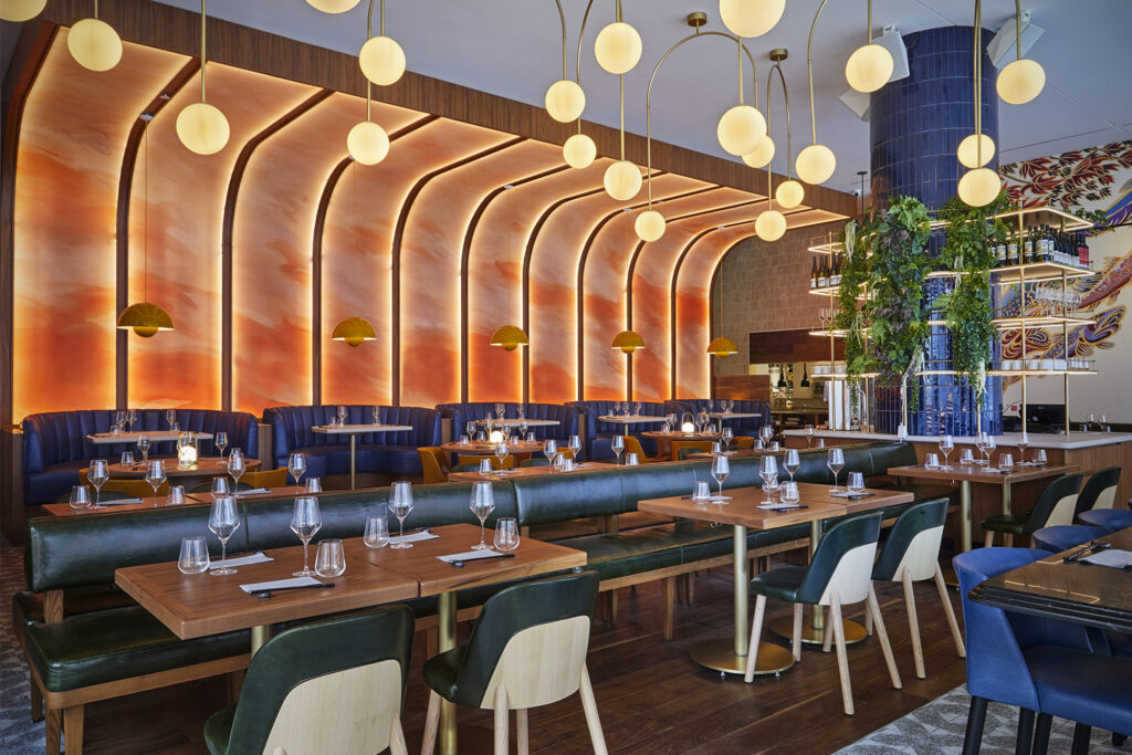 Interior of restaurant shows tables and an orange, art-deco background