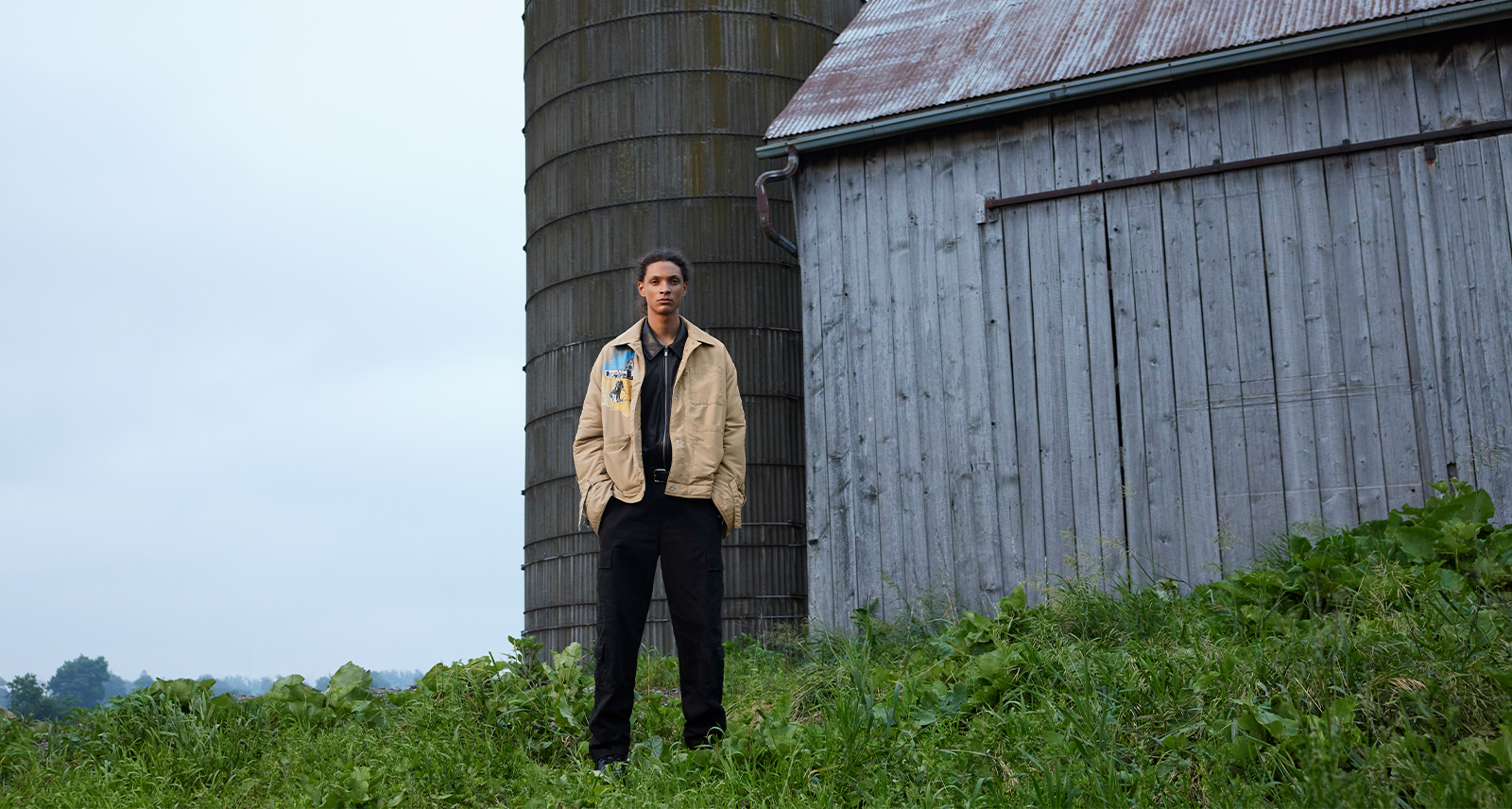 Man stands in front of a silo on a grey day
