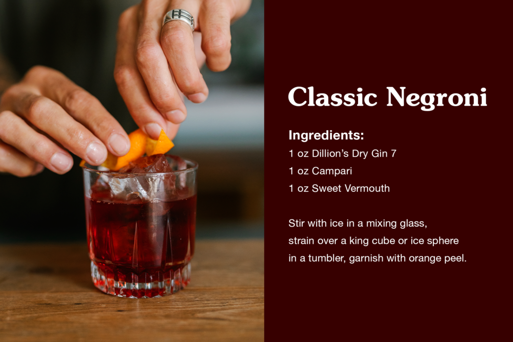 bartender squeezes an orange to top off a negroni in crystal glass. on the right, there is a negroni recipe Classic Negroni 

1 oz Dillion’s Dry Gin 7
1 oz Campari
1 oz Sweet Vermouth

Stir with ice in a mixing glass, strain over a king cube or ice sphere in a tumbler, garnish with orange peel. 
