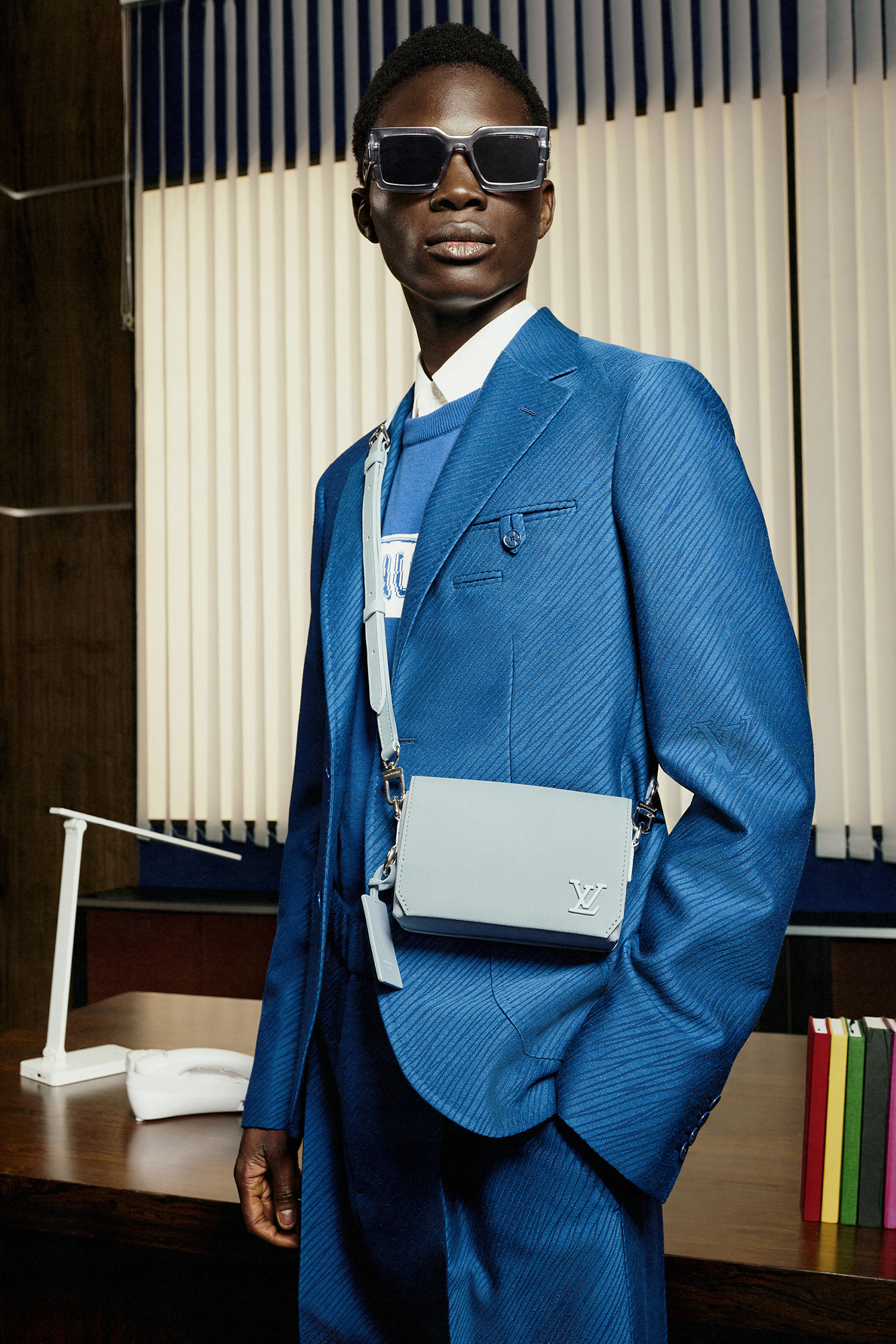 Model in blue suit with light grey-blue bag and black sunglasses for Louis Vuitton Studio Prêt-à-Porter Homme
