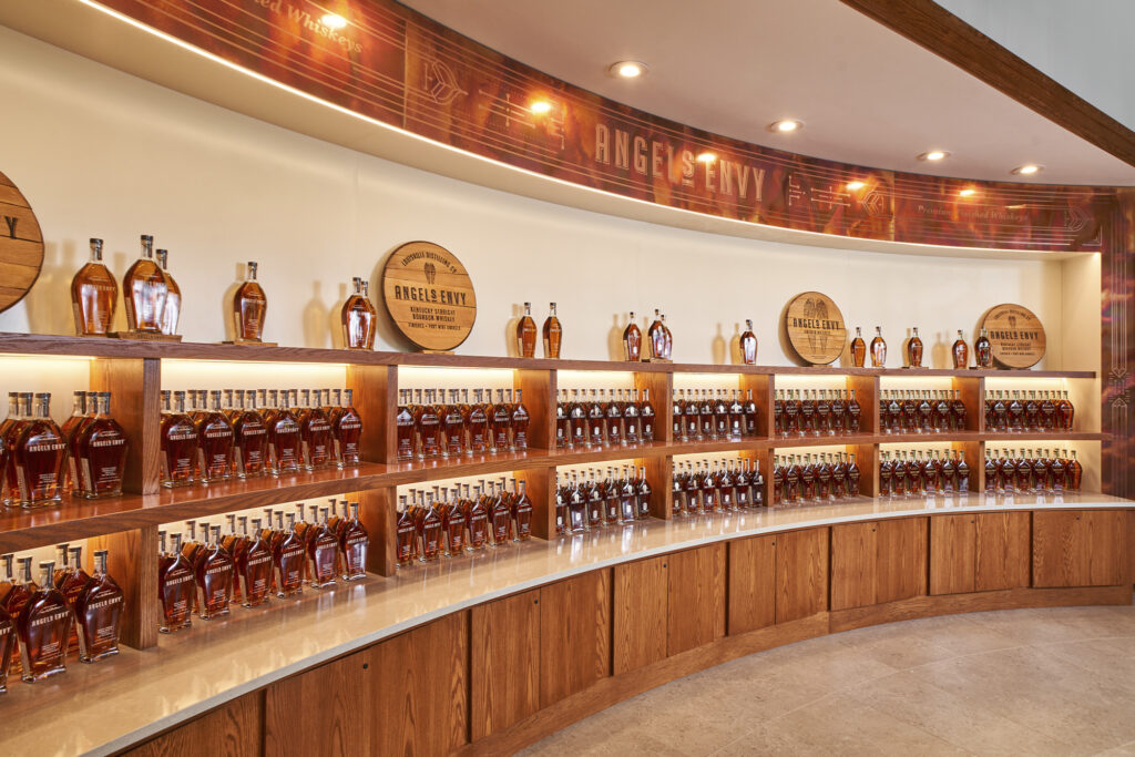 A curved wall showcases bottles of Angel's Envy whisky bourbon inside the distillery