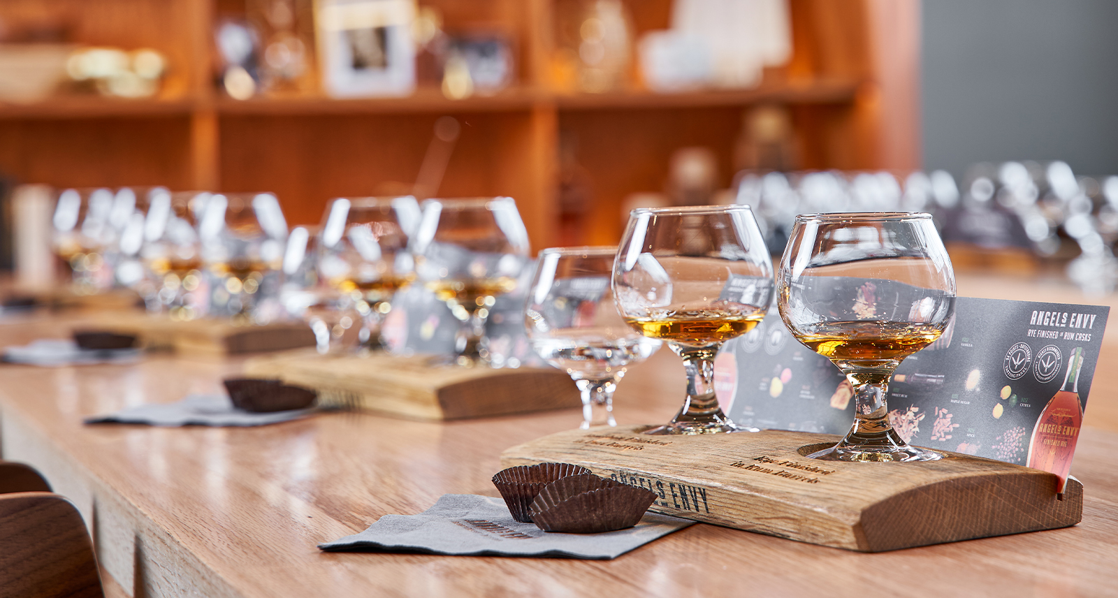 Angel's Envy a long table is set with whisky glasses and wooden fixtures