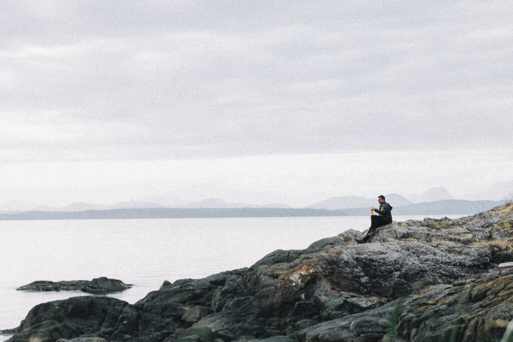 man sits on a rocky shore