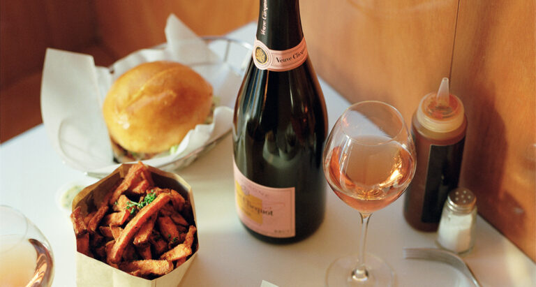 Bottles of Moet pink champagne with sweet potato fries, a glass of rose, and burgers