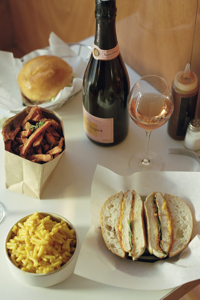 Bottles of Moet pink champagne with sweet potato fries, a glass of rose, and burgers