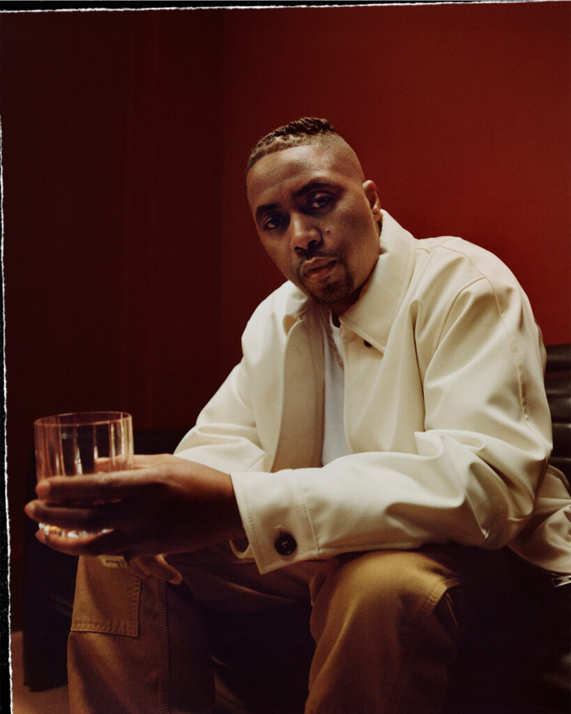 Nas posing with a glass of hennessy