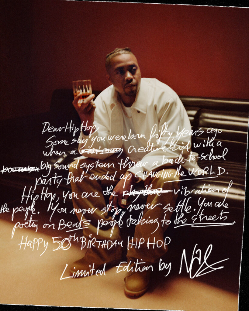 Nas posing with a glass of hennessy behind his letter for the 50th anniversary of hip-hop