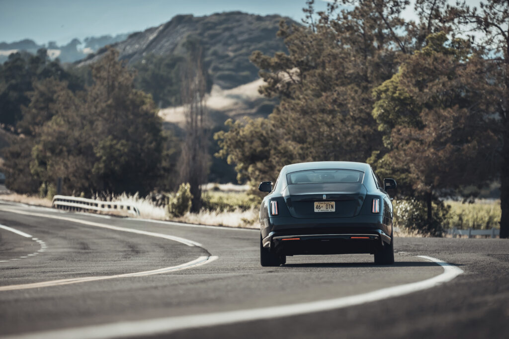 Rolls-Royce Spectre driving on the highway, shot from back