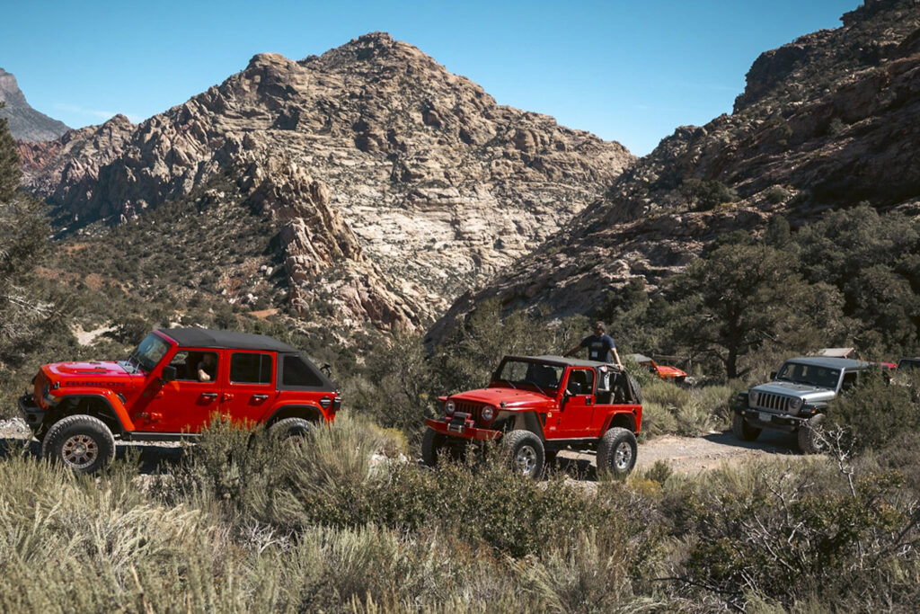 a line of jeep wranglers drive across the desert