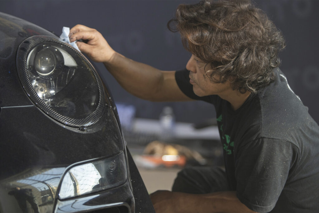 Akira Nakai works on the light of a Porsche