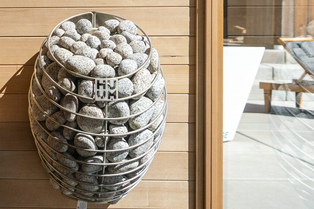 rocks in a wire basket outside hanging on a sauna